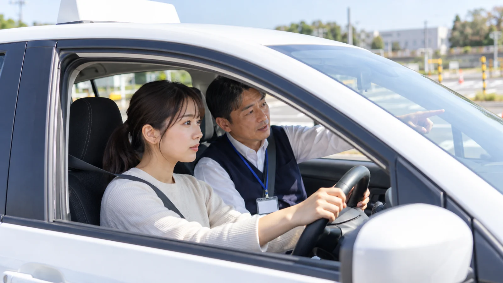 教習車の助手席から、指導員が運転する教習生に説明している様子